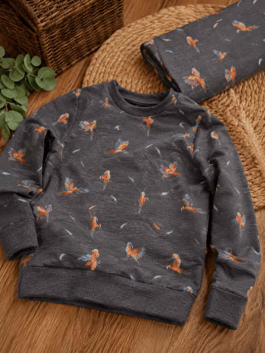 Image with cotton knit parrots on a dark gray background 200 g/m² – available online at Šarlotes audumi