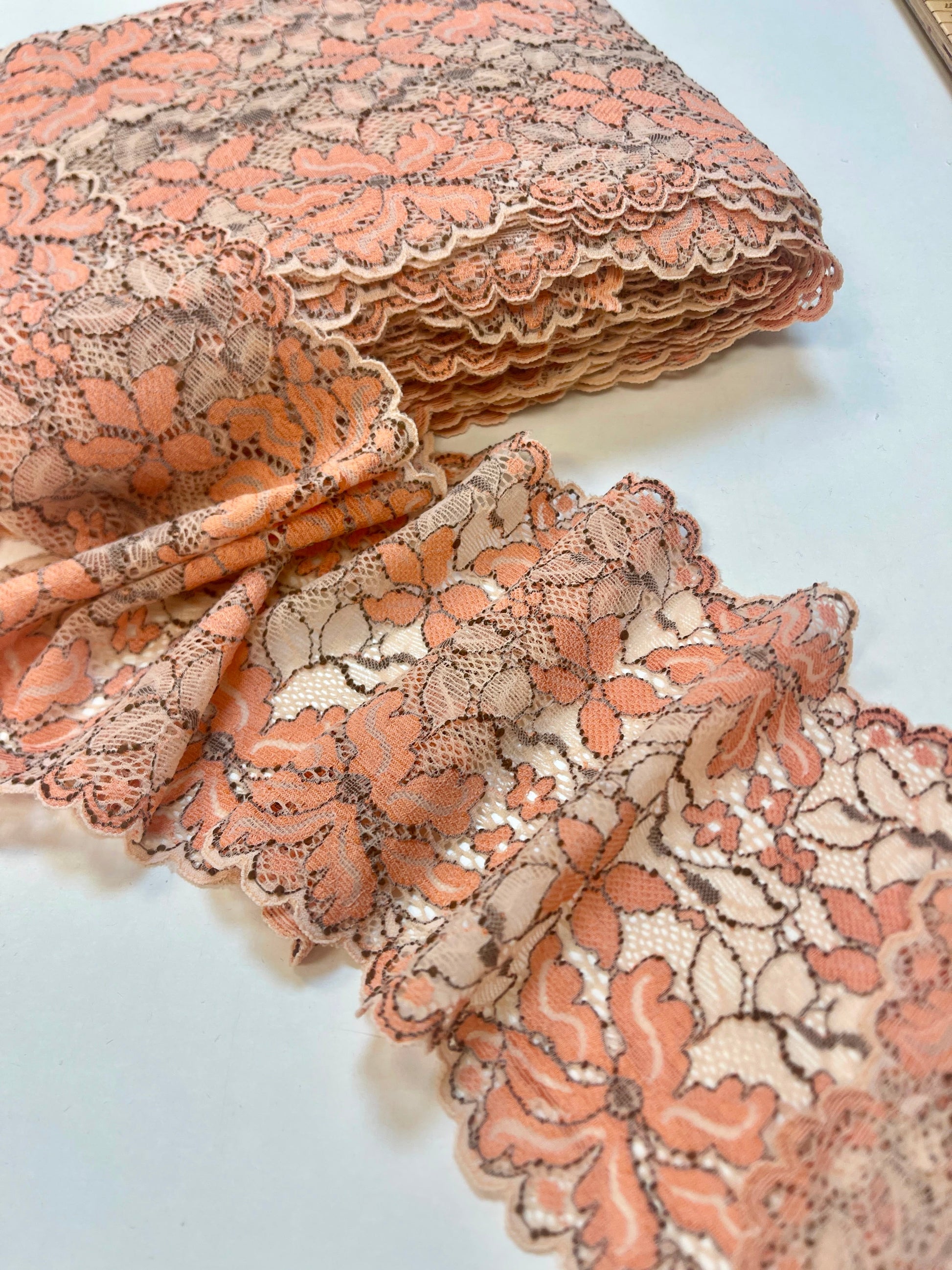 Image avec dentelle extensible de 14 cm, fleurs orange et fond beige – disponible en ligne chez Šarlotes audumi