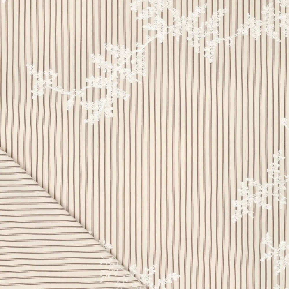 Image d’un tissu en coton brodé avec des lignes et des fleurs brodées blanches – disponible en ligne chez Šarlotes audumi