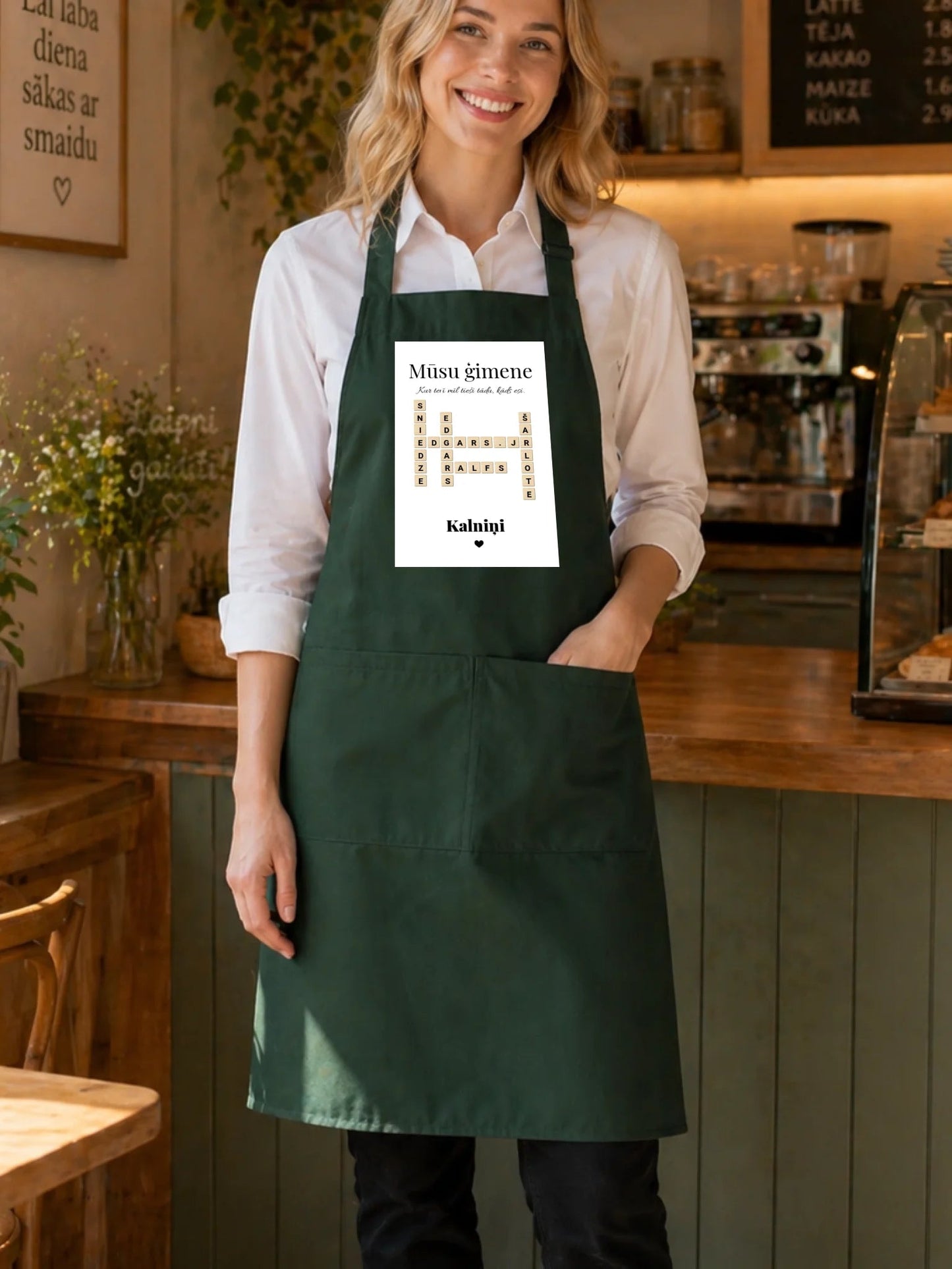 Image of a dark green "Scrabble" apron with family names – available from Charlotte's Fabrics