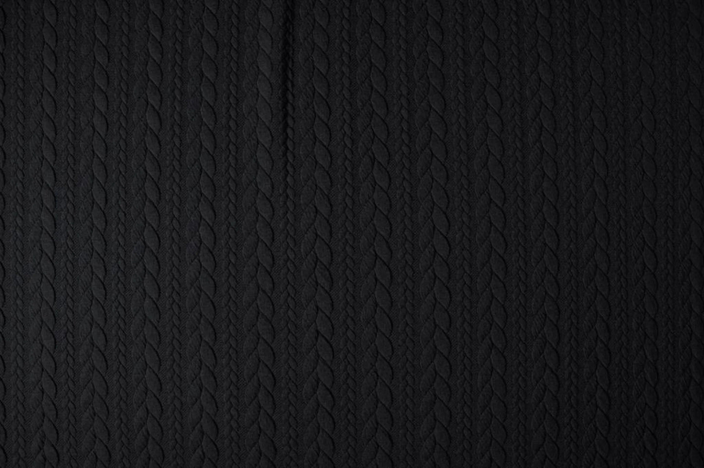 Image d’un tissu tricoté à motif de maille - tresses noires 340 g/m² – disponible chez Šarlotes audumi