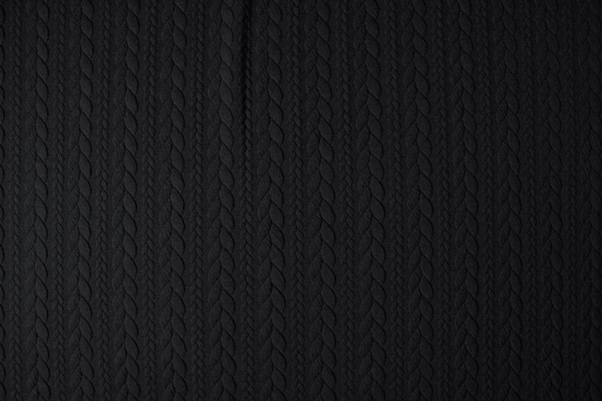 Image d’un tissu tricoté à motif de maille - tresses noires 340 g/m² – disponible chez Šarlotes audumi